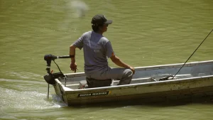 ชายนั่งท้ายเรือพร้อมมอเตอร์ไกด์ DELTA และแนวน้ำท้ายเรือ